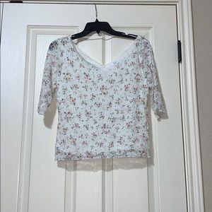 White shirt with pink flowers and green leaves.